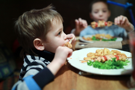 Kids eating kebab on skewers in restaurantの写真素材
