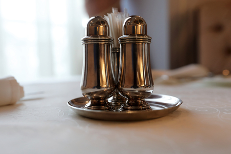 Metal salt and pepper shakers on tableの写真素材