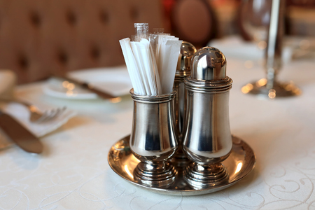 Metal salt and pepper shakers with toothpicks on tableの写真素材