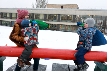 Boys fight on log with bags in winterの写真素材