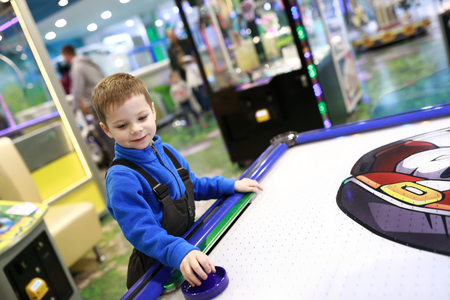 Smiling boy playing air hockey in amusement centerの写真素材