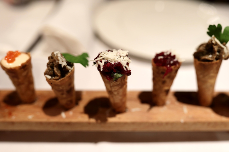 Various snack waffle cones on wooden plate in restaurant