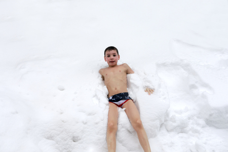 Portrait of topless child lying in snowの写真素材