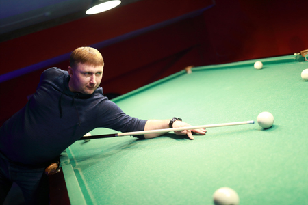 Portrait of man hits ball in billiards