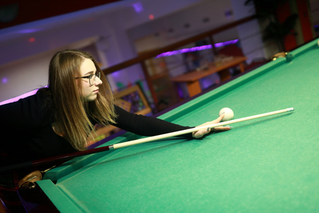 Portrait of girl playing billiards at night