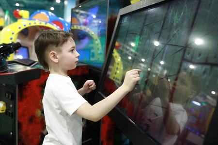 Kid plays game on large touch screen in amusement parkの写真素材