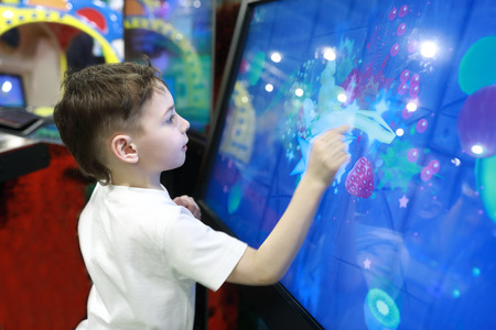 Child playing game on large touch screen in amusement park