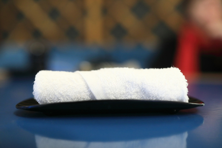 Rolled wet towel on plate in restaurantの写真素材