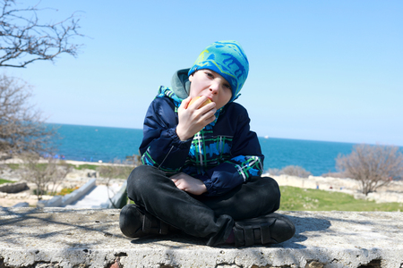 Child eating apple on embankment in Sevastopolの写真素材