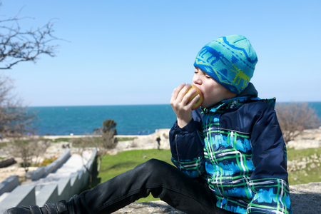 Boy eating apple on embankment in Sevastopolの写真素材