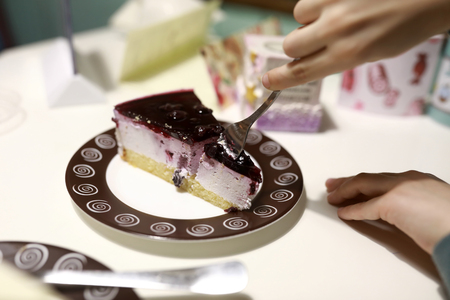 Person eating cake at table in cafeの写真素材