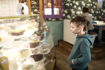 Boy choosing cake on showcase in cafeの写真素材