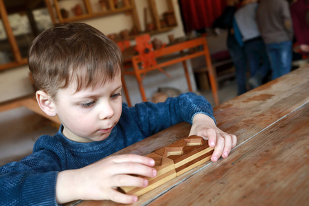 Child solves a wooden puzzle at tableの写真素材