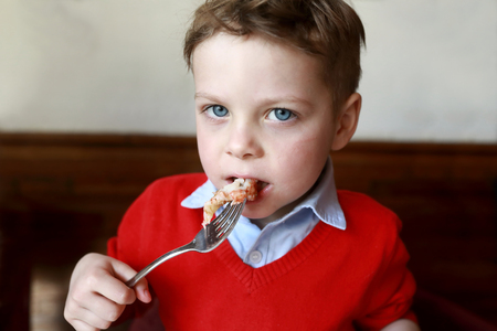 Hungry child eating shrimp in the restaurantの写真素材