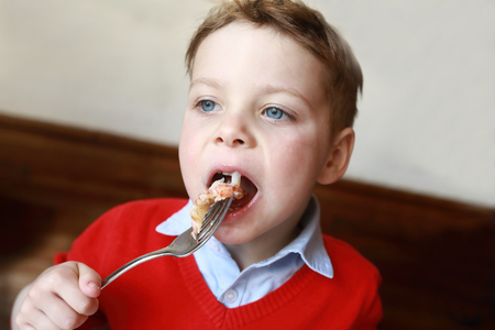 Hungry boy eating shrimp in the restaurantの写真素材