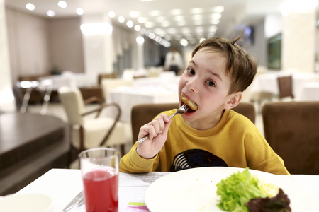 Kid eating chicken cutlet in a restaurantの写真素材