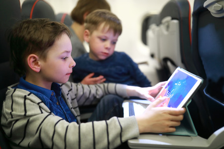 Boys using tablet in plane at night