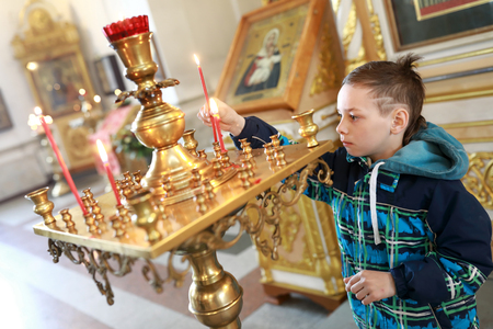 Boy lighting candle in russian orthodox churchの写真素材