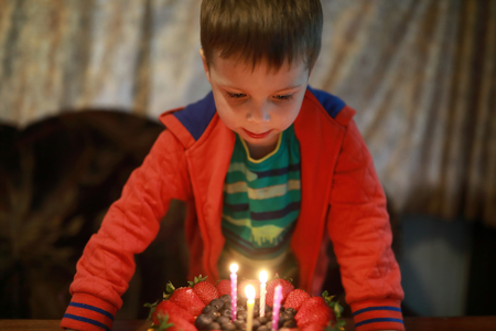 Boy blows out candles on birthday cakeの写真素材
