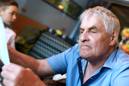 Elderly man with menu at table in restaurantの写真素材