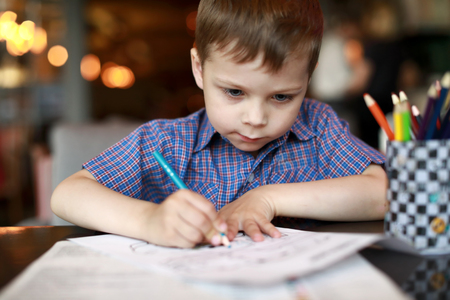 Child drawing with pencil in a cafeの写真素材