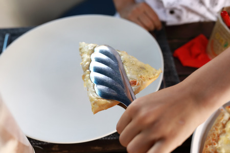 Person takes slice of pizza in restaurantの写真素材