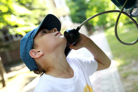Child talking on analog phone in telephone boothの写真素材