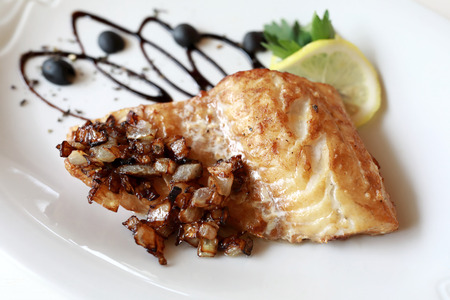 Fried pike perch with onions on plate