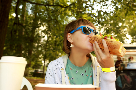 Woman has vegetable sandwich in the summer parkの写真素材