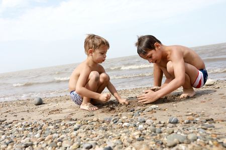 Children playing with pebbles on beach of Sea of Azovの写真素材