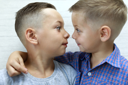 Brothers look at each other on wall backgroundの写真素材
