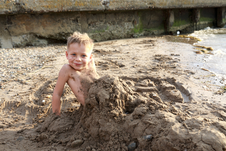 Preschooler buried in sand on beach of the Sea of ??Azovの写真素材
