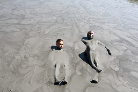 Grandfather with grandson lying in mud pool, Krasnodar region, Russiaの写真素材