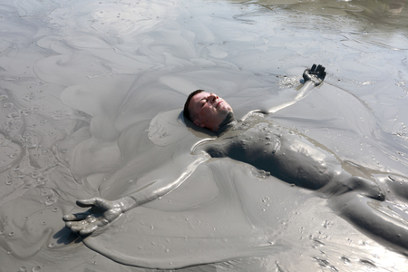 Portrait of man lying in mud pool