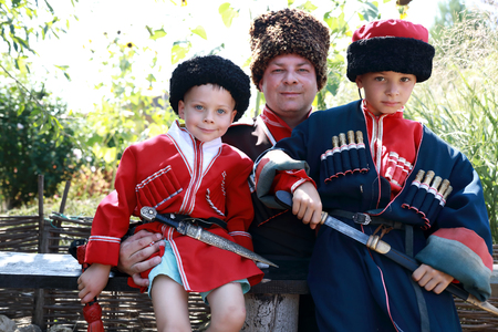 Father with sons in Cossack costumes in backyard