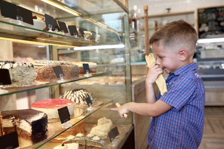 Child chooses cake in a cafe windowの写真素材
