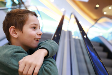 Boy standing on the escalator in mallの写真素材