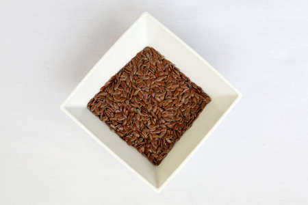 White plate with flax seeds on a tableの写真素材