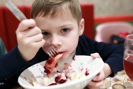 Kid eating cherry dumplings in a restaurantの写真素材