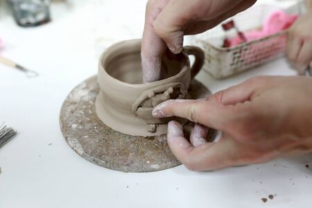 Person decorating clay cup in a workshop
