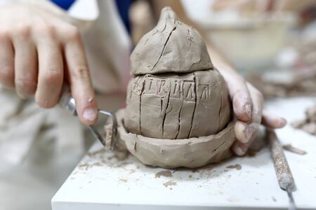 Person sculpts clay pumpkin in a workshopの写真素材