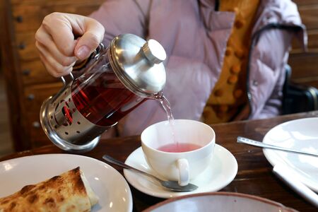 Woman pouring hibiscus tea in a restaurantの写真素材