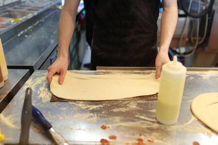 Chef prepares pizza dough on table at Pizzeria