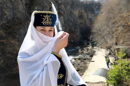 Woman covers her face with veil in traditional Karachai clothes, Kislovodsk, Russia