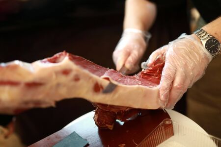 Seller cuts slice of jamon in market