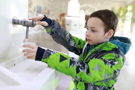 Boy pouring water in drinking pump room, Kislovodsk, Russiaの写真素材