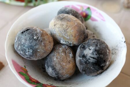 Bowl with charcoal baked potatoes on tableの写真素材
