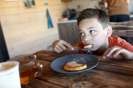 Boy eating pancakes with condensed milk at homeの写真素材