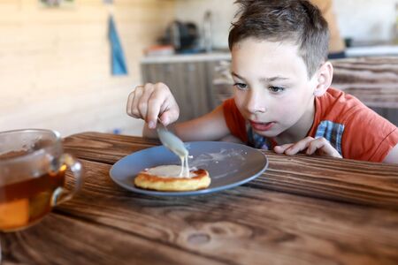 Child eating pancakes with condensed milk at homeの写真素材