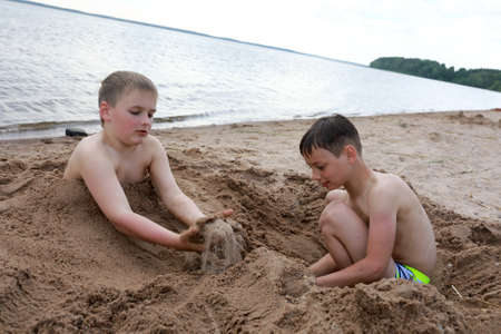 Two boys play on sandy beach of Lake Seliger, Ostashkov, Russiaの写真素材